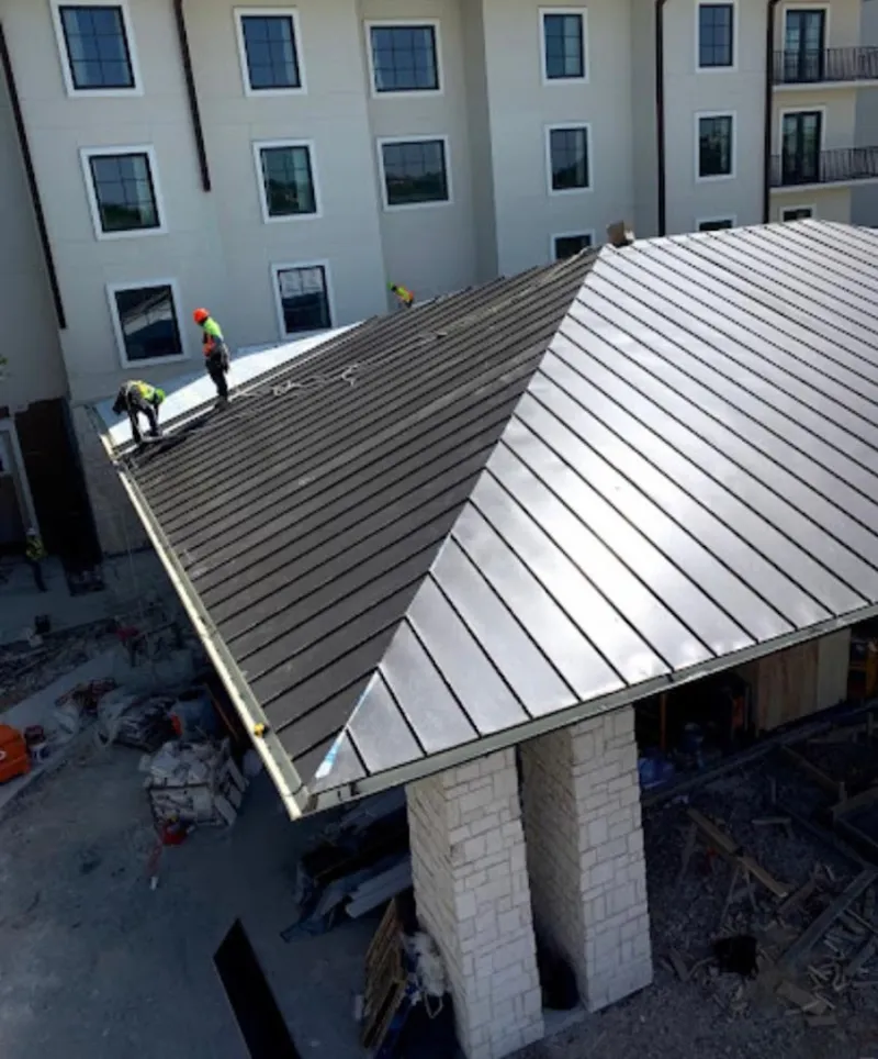 Crew installing standing seam metal roof panels on a commercial project in Yukon